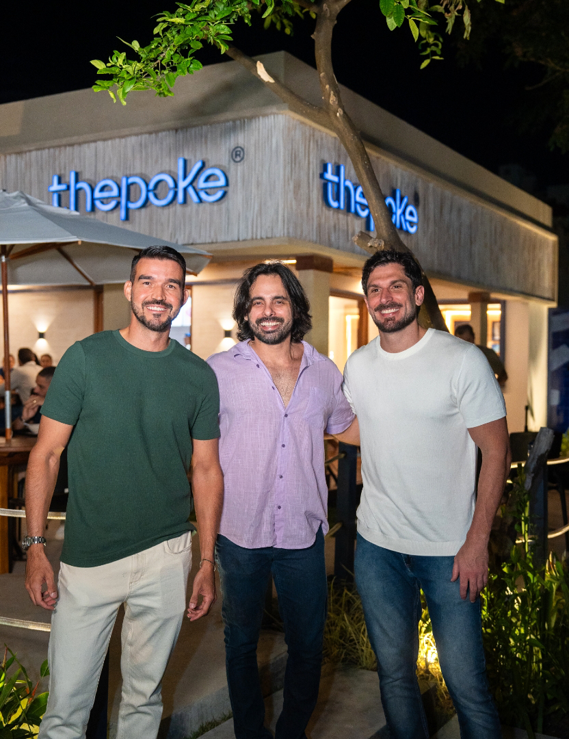 Fundadores da Thepoke em frente a uma unidade da marca